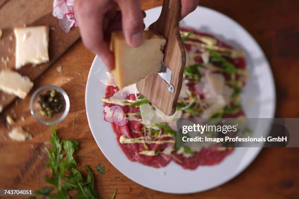 parmesan being grated over beef carpaccio - carpaccio stock-fotos und bilder