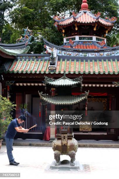 thian hock keng temple.  a chinese man praying and offering incense.  buddhist worshipper. burning incense sticks.  singapore. - singapore thian hock keng temple photos et images de collection