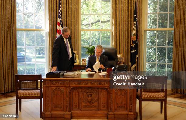 President George W. Bush and Councel to the President, Dan Bartlett, work in the Oval Office of the White House on October 26 in Washington, DC.