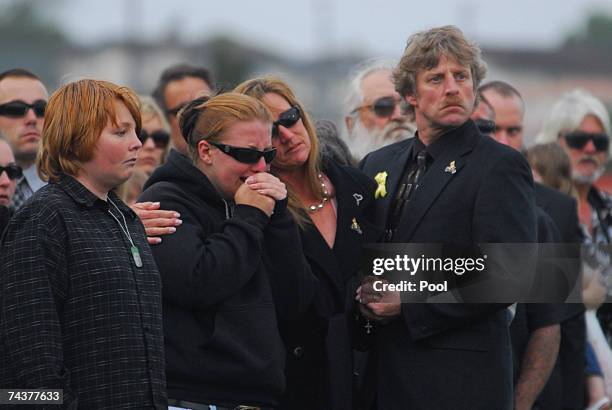 The Anzack family, sister Casey, mother Theresa and father Joseph, Sr., listen as "Taps" is played during a funeral service for Cpl. Joseph Anzack,...