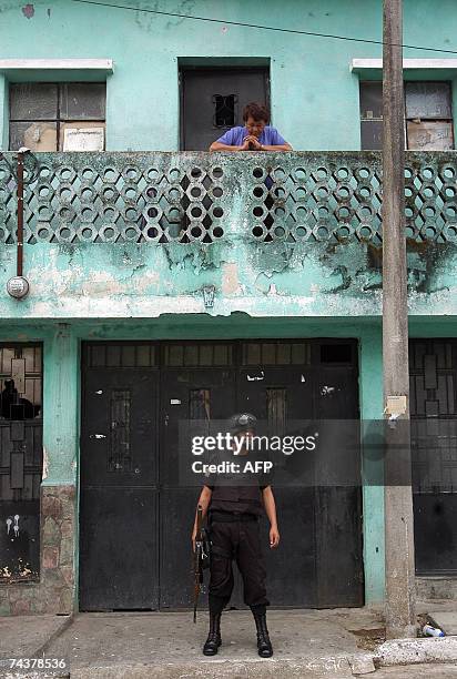 Guatemala City, GUATEMALA: Una vecina del barrio El Gallito de Ciudad de Guatemala, observa a un agente de la Policia Nacional mientras monta guardia...