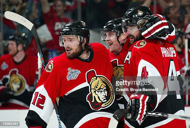 Mike Fisher of the Ottawa Senators celebrates with teammates Chris Phillips and Anton Volchenkov after scoring a tipped-in goal against the Anaheim...