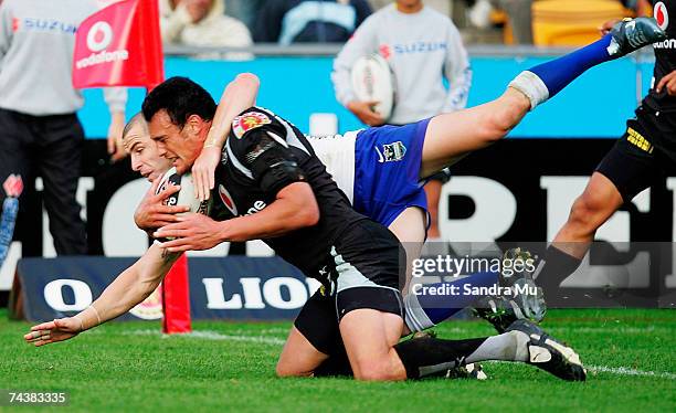 Luke Patten of the Bulldogs makes a tackle on Logan Swann of the Warriors as he scores a try during the round 12 NRL match between the Warriors and...