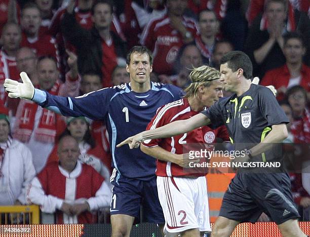 Danish goalkeeper Thomas Sorensen reacts to defender Christian Poulsen's red card handed to him by German referee Herbert Fandel who points to a...