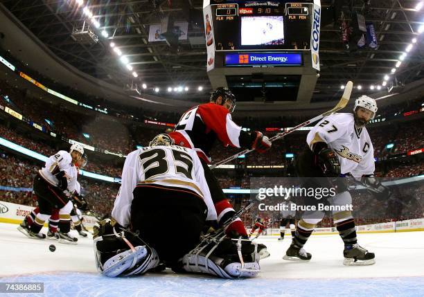 Scott Niedermayer of the Anaheim Ducks is hit by Jason Spezza of the Ottawa Senators in front of Jean-Sebastien Giguere during Game Three of the 2007...