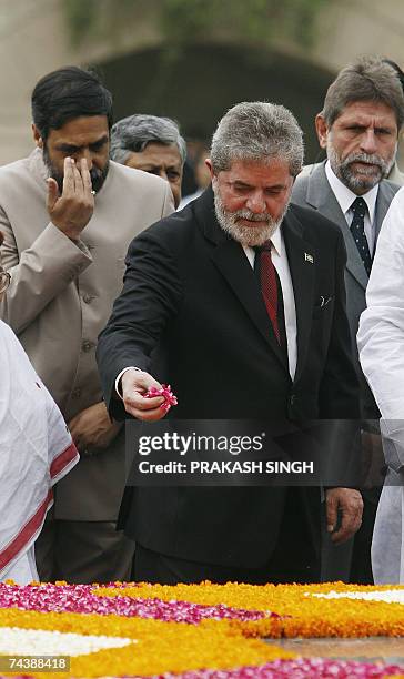 Brazilian President Luiz Inacio Lula da Silva tosses rose petals while paying tribute at Rajghat memorial for Mahatma Gandhi, as Indian Minister of...