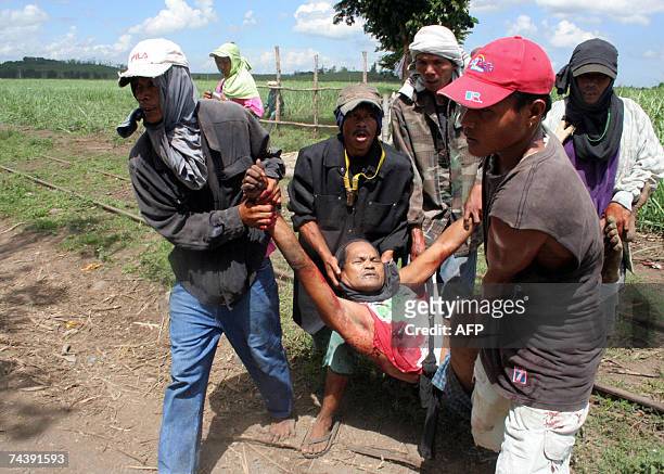 Farmers carry Ely Tupas, seriously bleeding from a gunshot wound after private guards of the sugar farm allegedly fired upon the group of Tupas who...