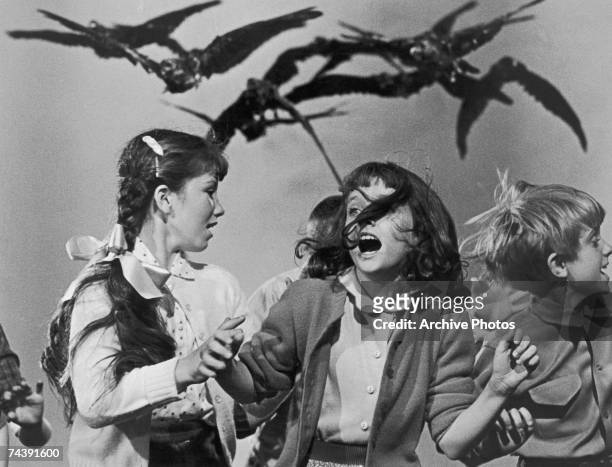 Group of schoolchildren flail about in terror at the avian attack in a publicity still for 'The Birds', directed by Alfred Hitchcock for Universal,...