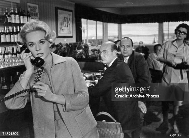 American actress Tippi Hedren makes a telephone call in a scene from 'The Birds', directed by Alfred Hitchcock for Universal, 1963. Just behind her...