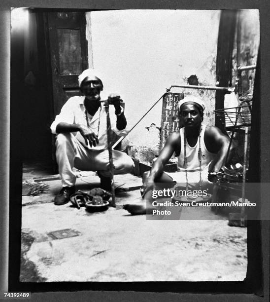 Santeria "babalawo" Juliano and priest Enrique pose on October 21, 1998 in the old town in Havana, Cuba. Juliano holds a "Baku" and kneels in front...