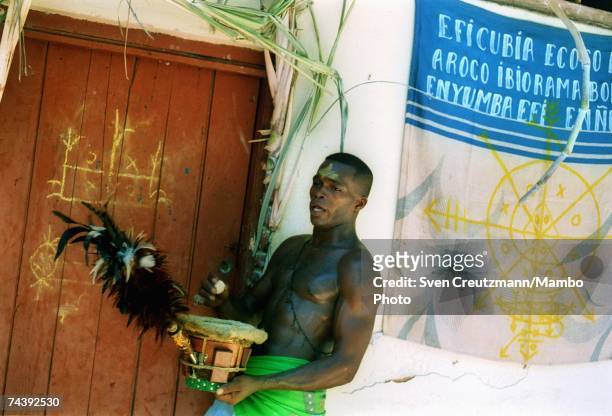 Nianigo", member of the Abacua society, knocks on the door of the Abacua temple holding a drum and feather brush during a two-day initiation rite for...