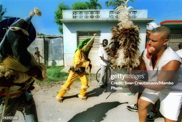 Two "Ireme" or "Diablito" dance the "Efori Isun" with a "Nianigo" , who holds the head of a chicken in his mouth, at a ceremony to consecrate the...
