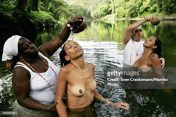 Two women have river water poured on their heads during a Santeria ritual cleansing by two "santeros" on July 31, 2006 near Havana, Cuba. Santeria...