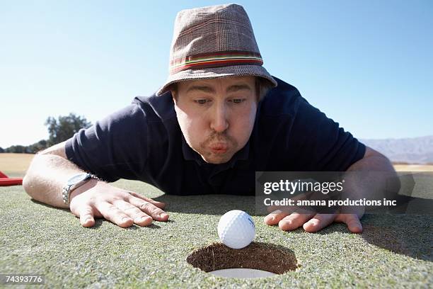 man blowing golf ball to hole - golf cheating foto e immagini stock