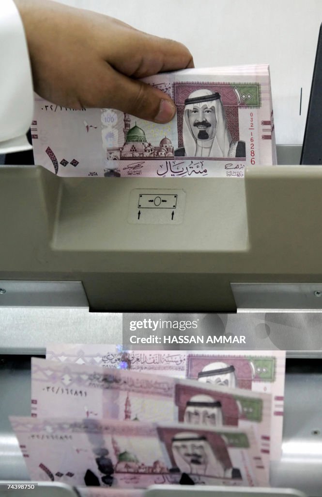A Saudi banker counts new one hundred ri...