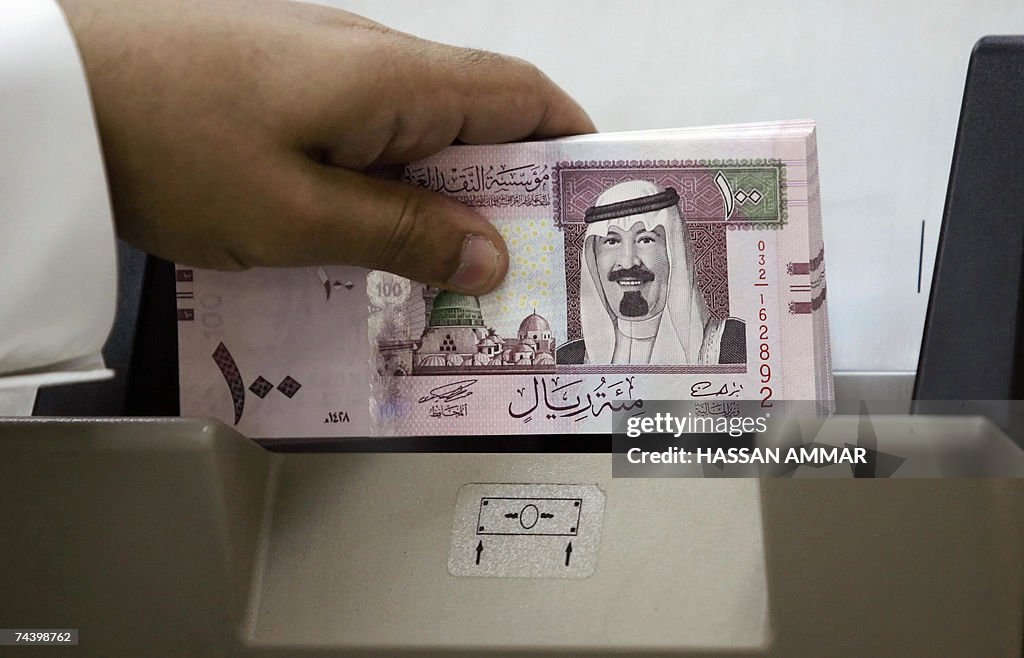 A Saudi banker counts new one hundred ri...