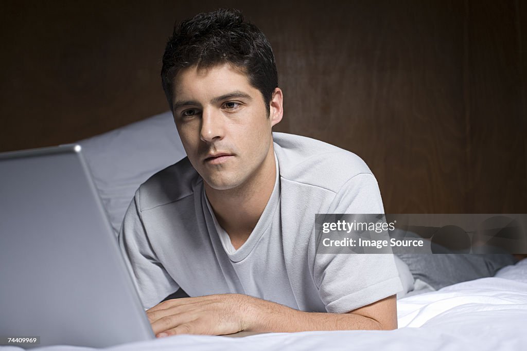 Young man using laptop on bed