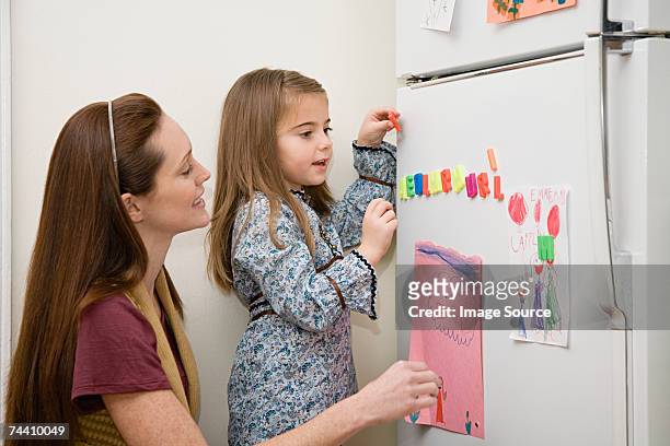 mother and daughter by refrigerator - fridge magnet stock pictures, royalty-free photos & images