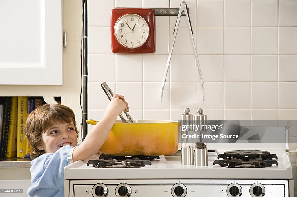 Boy reaching up to saucepan