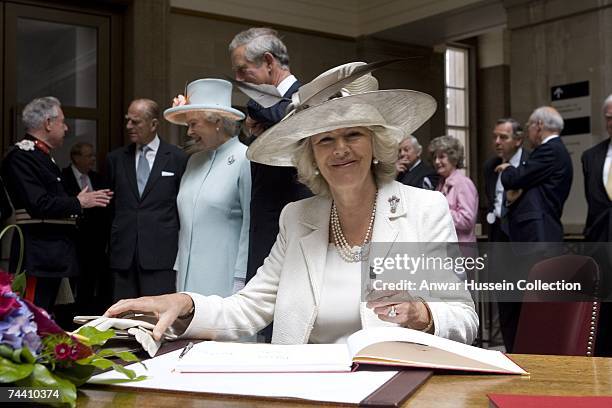 Camilla, Duchess of Cornwall signs the visitors book during her visit with Prince Charles, Prince of Wales, Queen Elizabeth II and Prince Philip,...