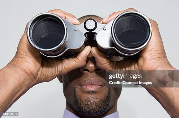 man looking through binoculars - mirar a través fotografías e imágenes de stock