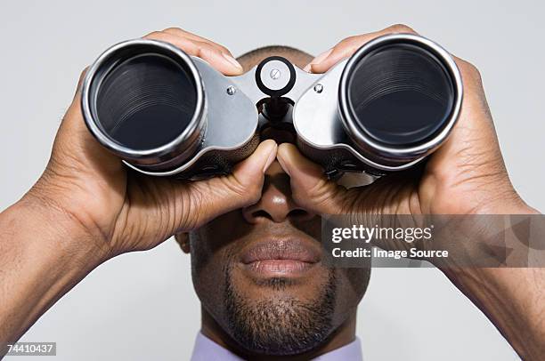 man looking through binoculars - binoculars imagens e fotografias de stock