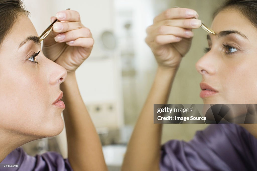 Woman plucking eyebrows