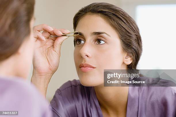 woman plucking eyebrows - tweezing eyebrows stock pictures, royalty-free photos & images