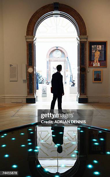 London, UNITED KINGDOM: A visitor walks past an installation "Time in Water," a work comprising waterproof LEDs submerged in water, on show at the...