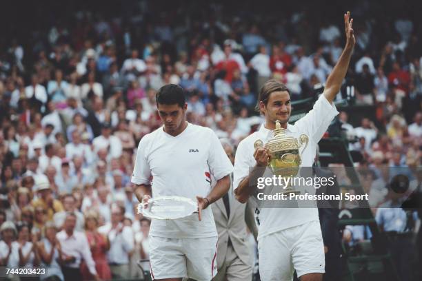 Swiss tennis player Roger Federer waves his arm in the air as he holds the Gentlemen's Singles Trophy after beating Mark Philippoussis of Australia,...