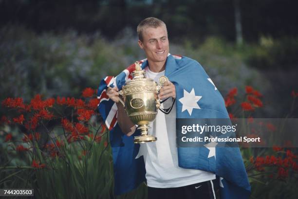 Australian tennis player Lleyton Hewitt, wrapped in the national flag of Australia, holds the Gentlemen's Singles Trophy after beating David...