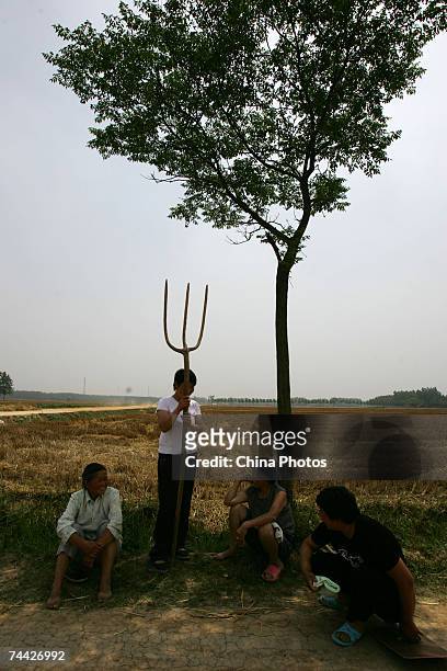 Farmers rest after reaped wheat by hand in a field on June 5, 2007 in the outskirts of Taihe County of Fuyang, Anhui Province, China.In its monthly...