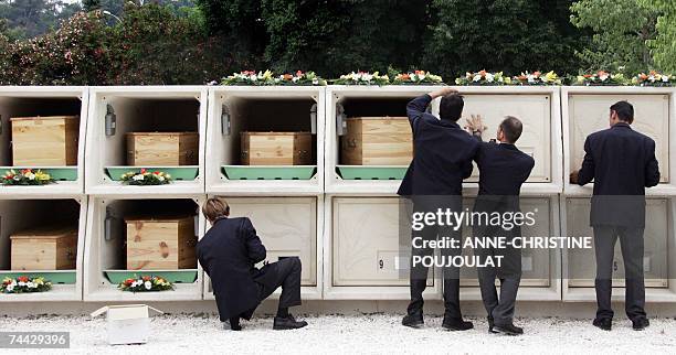 Cemetery employees close the lockers containing coffins, 07 June 2007 in Toulon, during the ecumenical funerals of the 18 migrants found floating at...