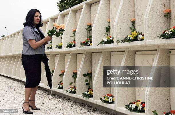 Woman lays down roses on the lockers containing coffins 07 June 2007 in Toulon, during the ecumenical funerals of the 18 migrants found floating at...