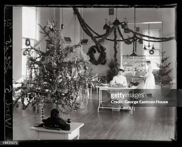 View of Christmas decorations in Ward 5 of Presbyterian Hospital, New York, New York, December 25, 1903. The ward's head nurse sits at a table in the...