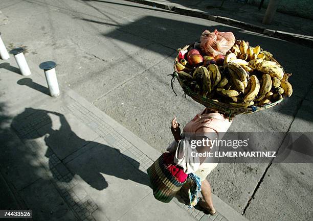 Tegucigalpa, HONDURAS: Sulema Garcia carga en su cabeza un cesto con frutas para vender en la calle de un barrio en Tegucigalpa, el 07 de junio de...