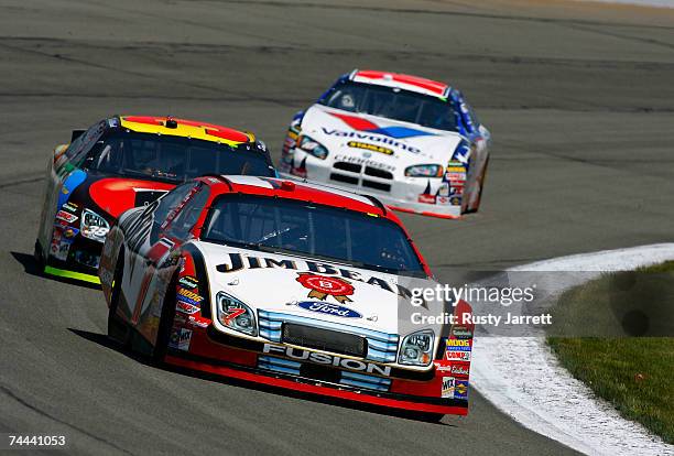 Robby Gordon, driver of the Jim Beam Ford, leads David Gilliland, driver of the M & M's Ford, and Scott Riggs, driver of the Valvoline/Stanley Tools...