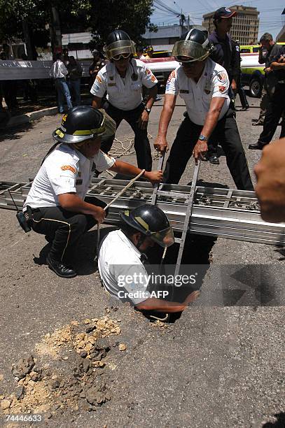 Bomberos Voluntarios inspeccionan un agujero que se formo tras producirse un socavon de 10 metros de diametro a raiz del colapso de drenajes en un...