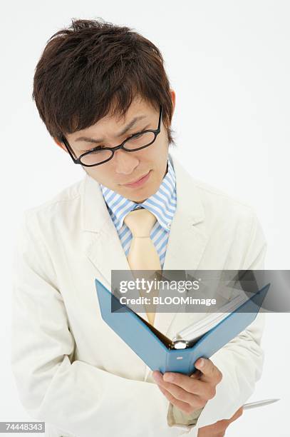 japanese businessman wearing glasses looking at schedule book - cross stripes shirt stockfoto's en -beelden