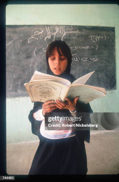 Young girl wearing a hijab reads a book in class at Jalalabad all-girls school March 15, 1993 in Kabul, Afghanistan. Since the Islamic government...