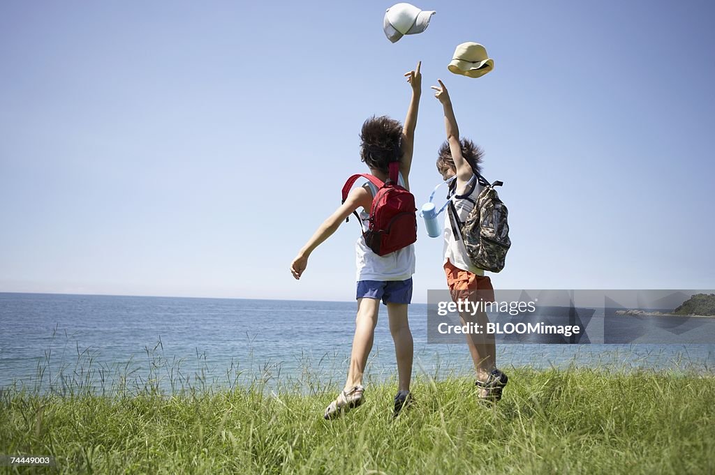 Japanese boys jumping with looking at seascape on hill