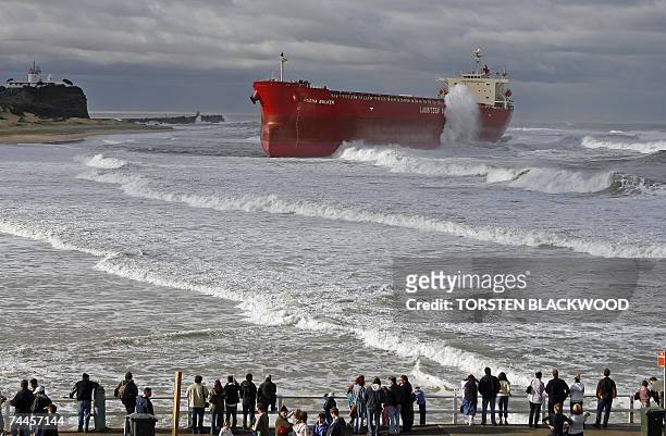 Locals watch wild seas pound the 30,000-tonne bulk coal carrier 'Pasha Bulker' which ran aground off Nobbys Beach in Newcastle, north of Sydney, 09...
