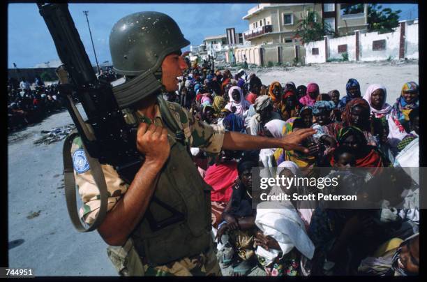 United Nations soldier stands over a group of Somali people June 6, 1993 in Mogadishu, Somalia. UN troops seized the residence of General Mohammad...