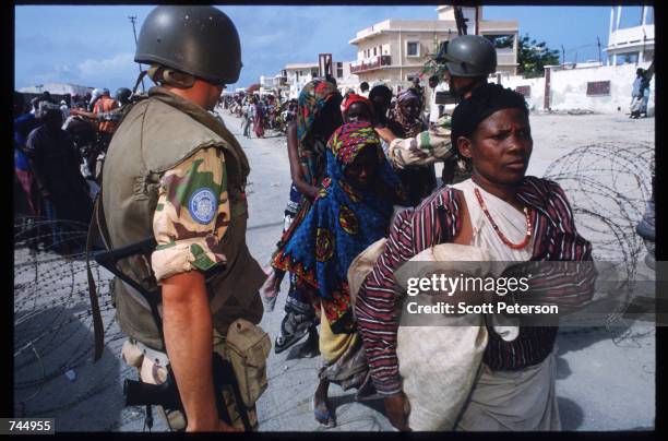 United Nations soldier stands among Somali people June 6, 1993 in Mogadishu, Somalia. UN troops seized the residence of General Mohammad Aidid, a...