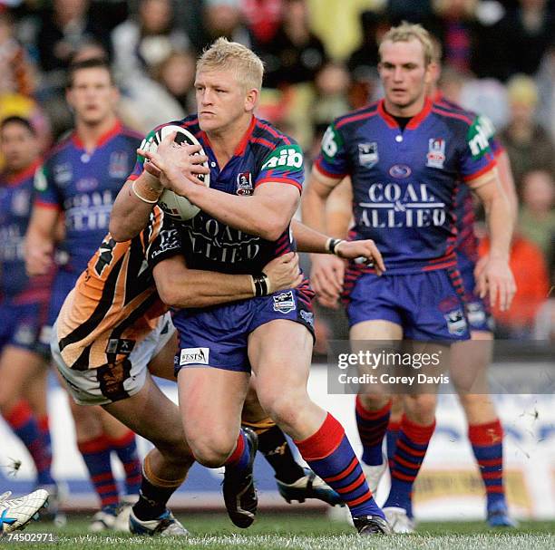 Mitchell Sargent of the Knights is tackled by Tigers defence during the round 13 NRL match between the Newcastle Knights and the Wests Tigers at...