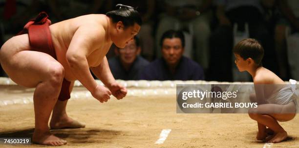 Honolulu, UNITED STATES: A young boy lines up against a professional sumo wrestler during an exhibition before the start of the first day of the...