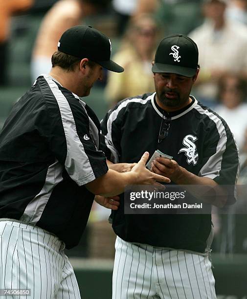 Manager Ozzie Guillen of the Chicago White Sox hands the line-up card to pitcher Mark Buehrle after Buehrle notched his 100th career win against the...