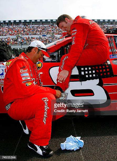 Dale Earnhardt Jr., driver of the Budweiser Chevrolet, is helped into his car by a crew member in order to keep his feet dry on pit road prior to the...