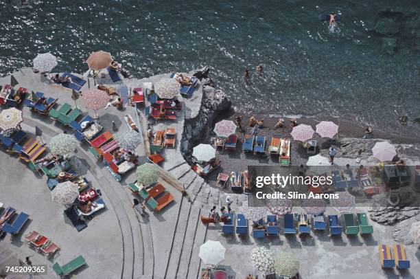 Elevated view looking down on sunbathers and parasols on the beach at La Scogliera beach in Positano, Italy, 1979.