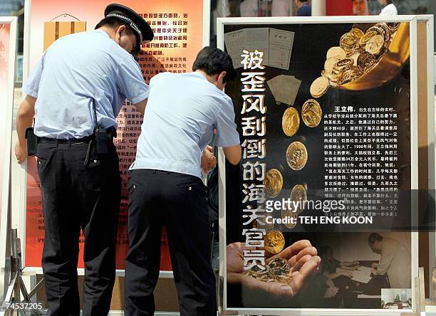 Chinese policemen set up anti corruption billboards on display in Central Beijing, 11 June 2007. Unable to stem a rising tide of corruption, China is...